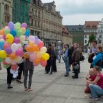 Vier Aktionsteilnehmerinnen mit Luftballons in der Hand und Passantinnen und Passanten darum auf dem Zwickauer Marktplatz
